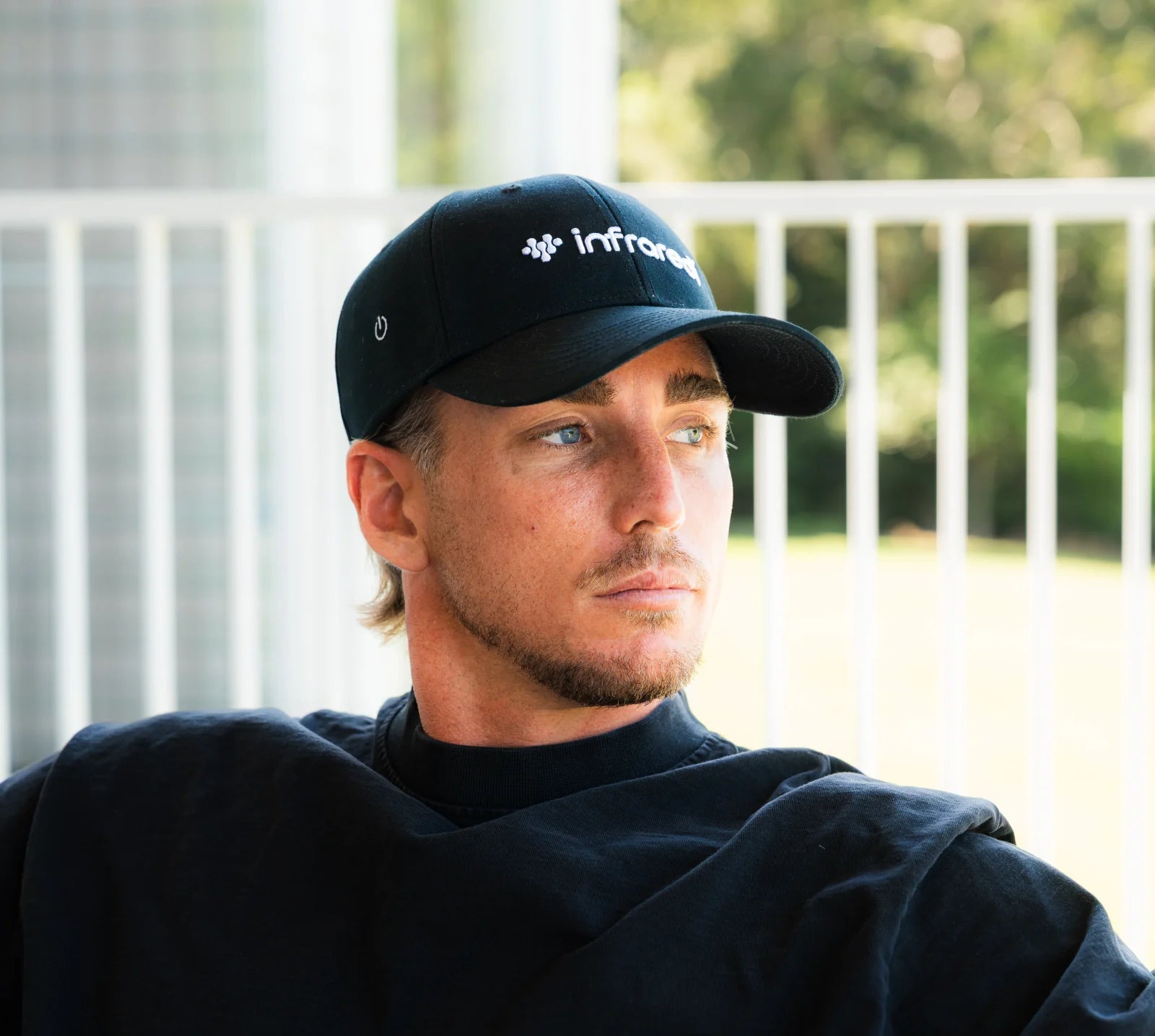 Man wearing the Infraredi Hair Growth Hat, relaxed on a verandah