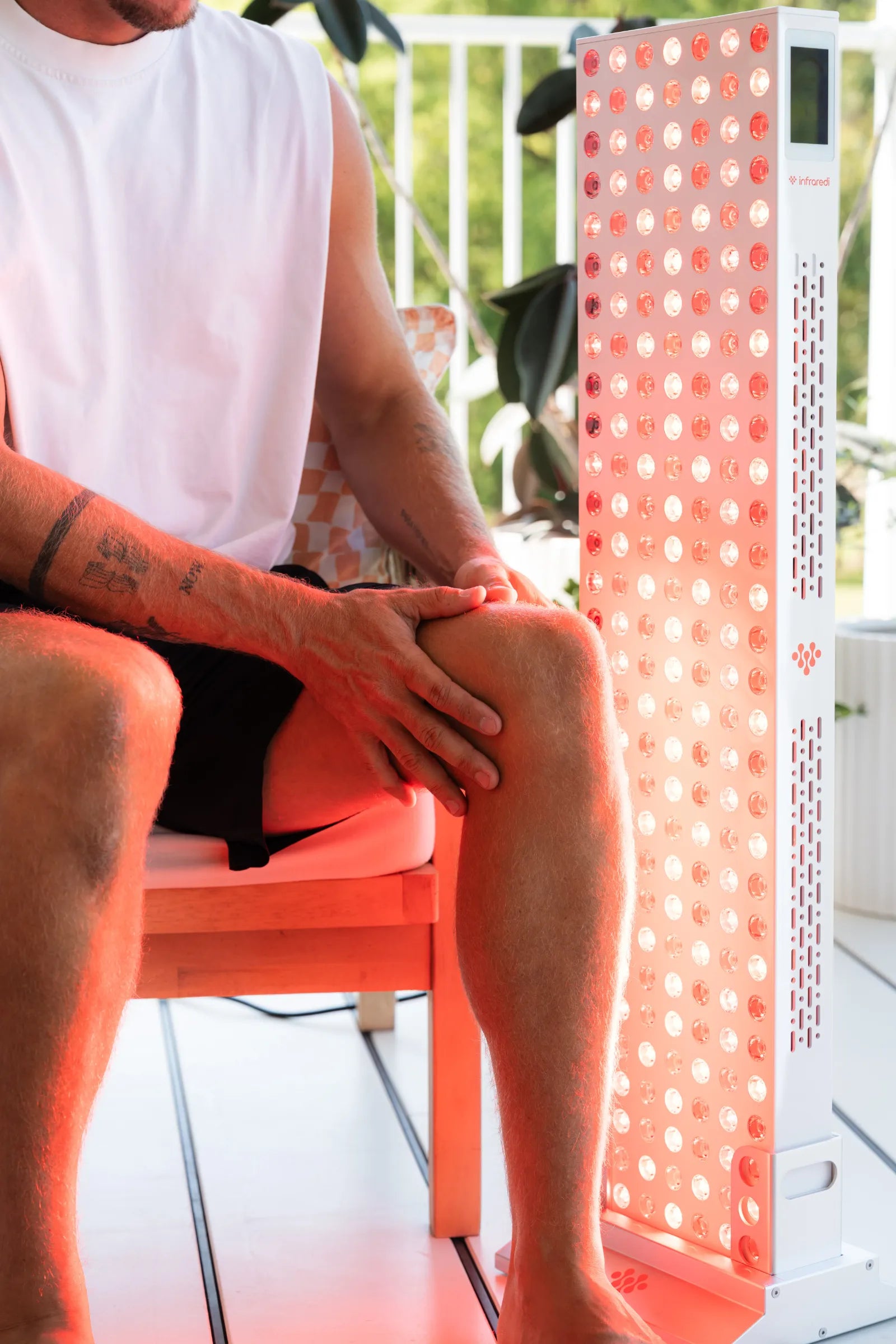 Man sitting beside an Infraredi Pro Max panel on a verandah